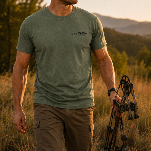 Man wearing field olive ARC Outdoors tee while holding a compound bow outdoors