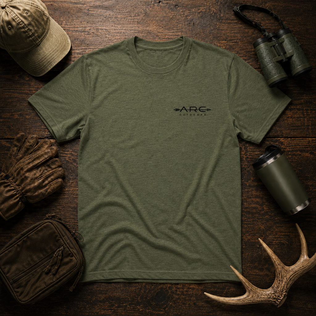 Field olive ARC Outdoors tee flat lay with outdoor gear and antlers