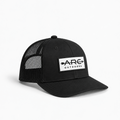 A black trucker-style cap with a white rectangular patch on the front that reads 'ARC OUTDOORS' with arrow graphics, shown on a clean white background.